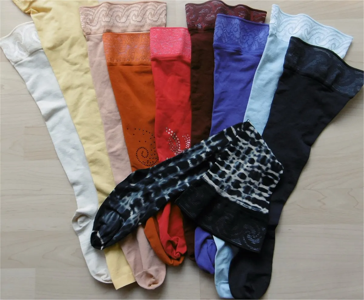 A fan of medical compression stockings in many colours and patterns laid flat on a light wooden surface